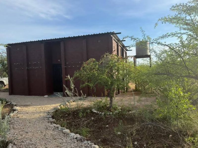 A detached masonry structure on a farm property featuring a metal roof and an elevated water storage tank.