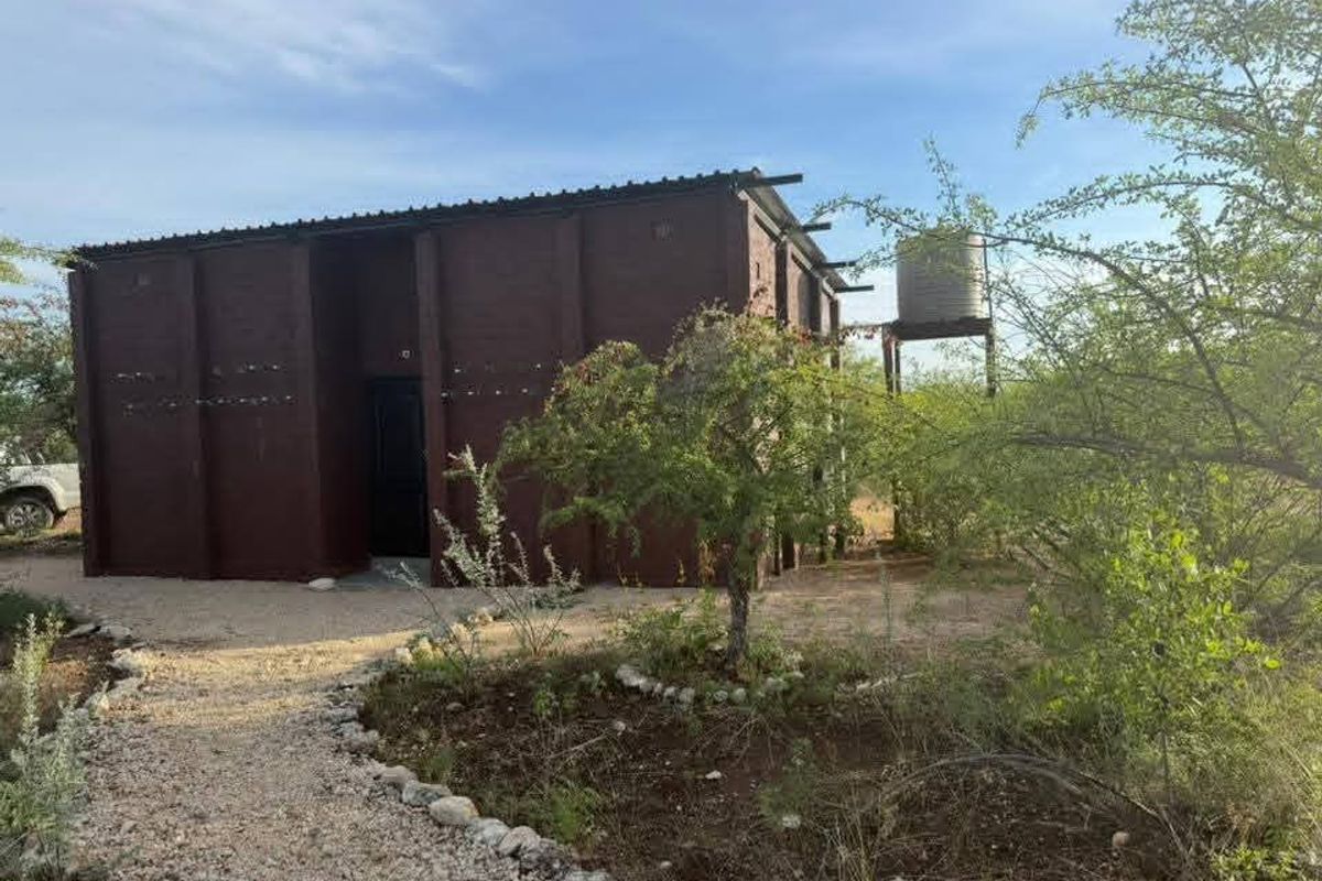 A detached masonry structure on a farm property featuring a metal roof and an elevated water storage tank.
