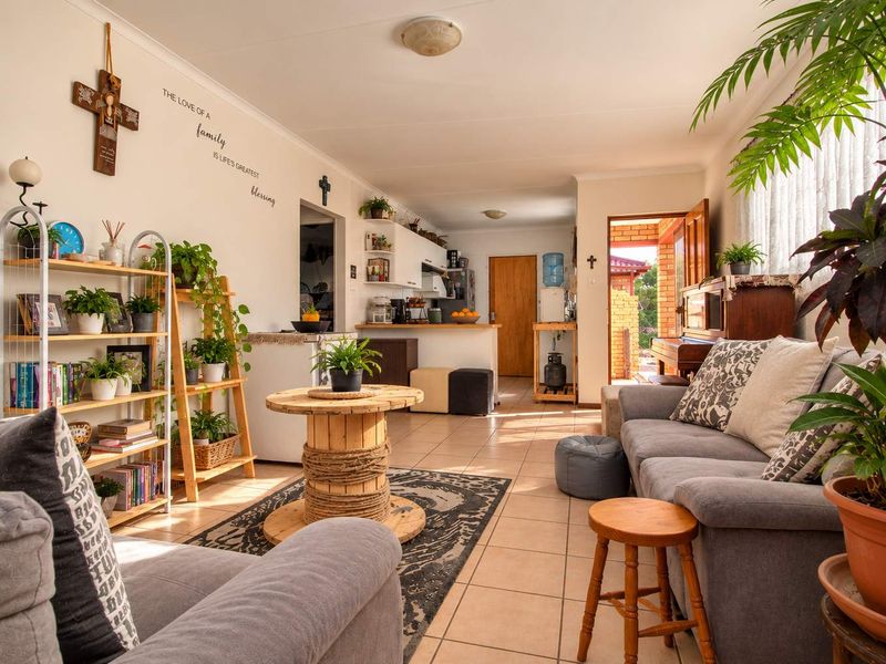 Open-plan living and kitchen area featuring tiled flooring, a breakfast counter, and direct access to an outdoor patio space.