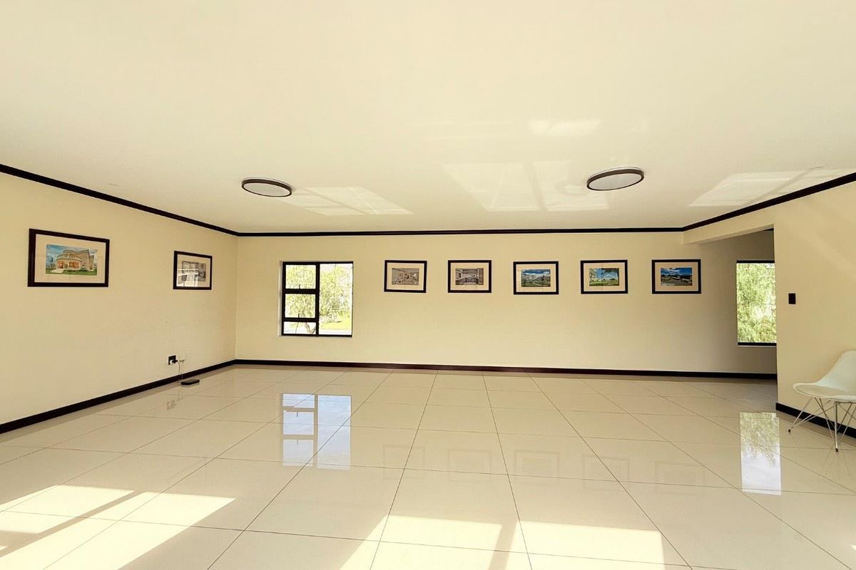 A spacious, bright, and empty living area featuring polished porcelain floor tiles, recessed ceiling lighting, and dark trim accents.