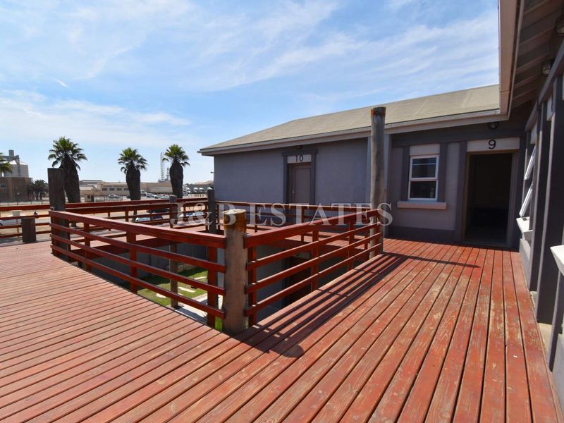 An elevated timber deck area providing access to commercial units, featuring wooden railings and views of the surrounding industrial estate.