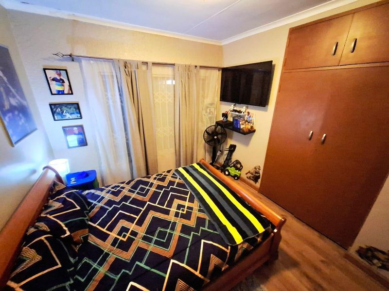 A functional bedroom featuring built-in wooden cupboards and laminate flooring, providing practical storage and a neutral foundation for interior design updates.