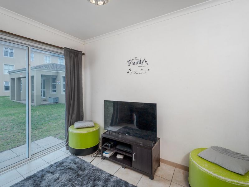 A living area featuring tiled flooring and a large sliding glass door providing direct access to the outdoor garden space.