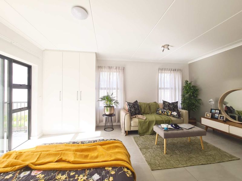Spacious bedroom featuring neutral tiled flooring, built-in cupboards, and a sliding glass door providing natural light and access to the exterior.
