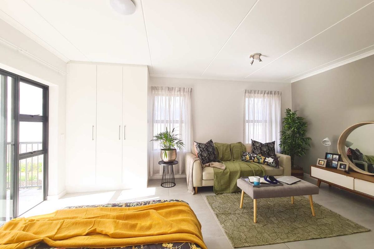 Spacious bedroom featuring neutral tiled flooring, built-in cupboards, and a sliding glass door providing natural light and access to the exterior.