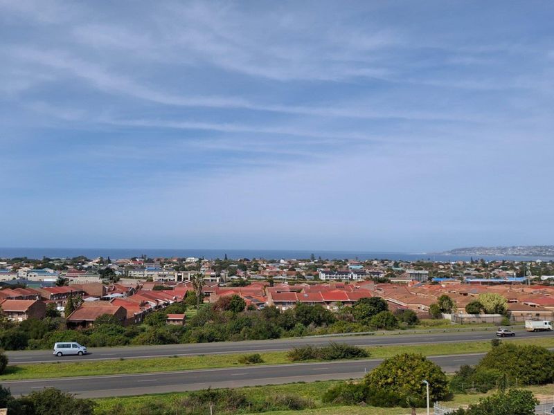An elevated panoramic view overlooking a residential neighborhood, highway, and the distant coastline.