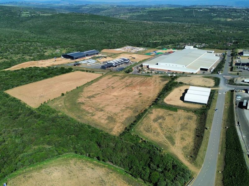 Aerial view of an industrial park featuring large warehouse facilities, paved access roads, and surrounding undeveloped land.