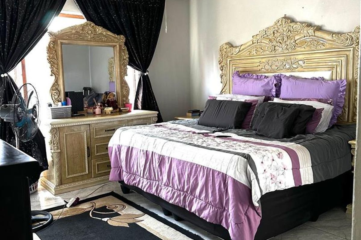 A bedroom featuring tiled flooring, a wall-mounted air conditioning unit, and a ceiling-mounted light fixture.