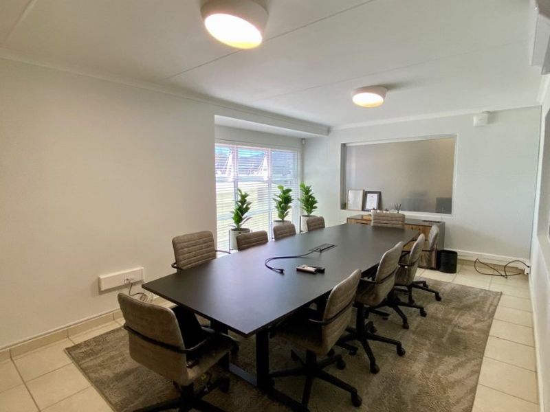 A functional office or boardroom space featuring tiled flooring, integrated lighting, and an internal window, suitable for professional meetings.