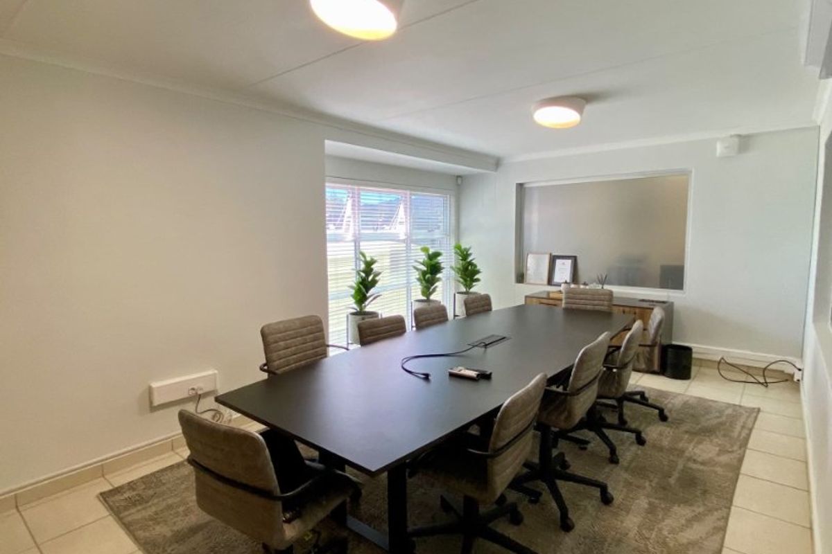 A functional office or boardroom space featuring tiled flooring, integrated lighting, and an internal window, suitable for professional meetings.
