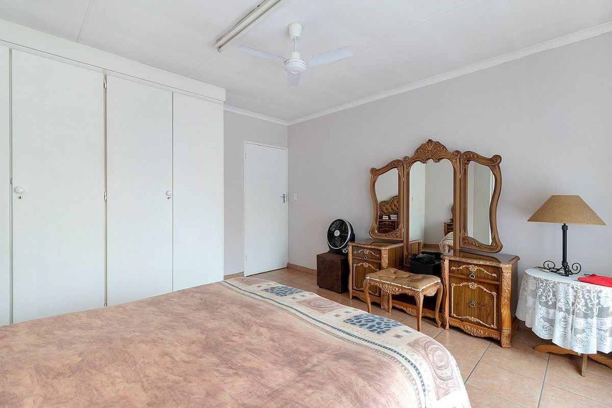 A bedroom featuring tiled flooring, built-in cupboards, and a ceiling fan.