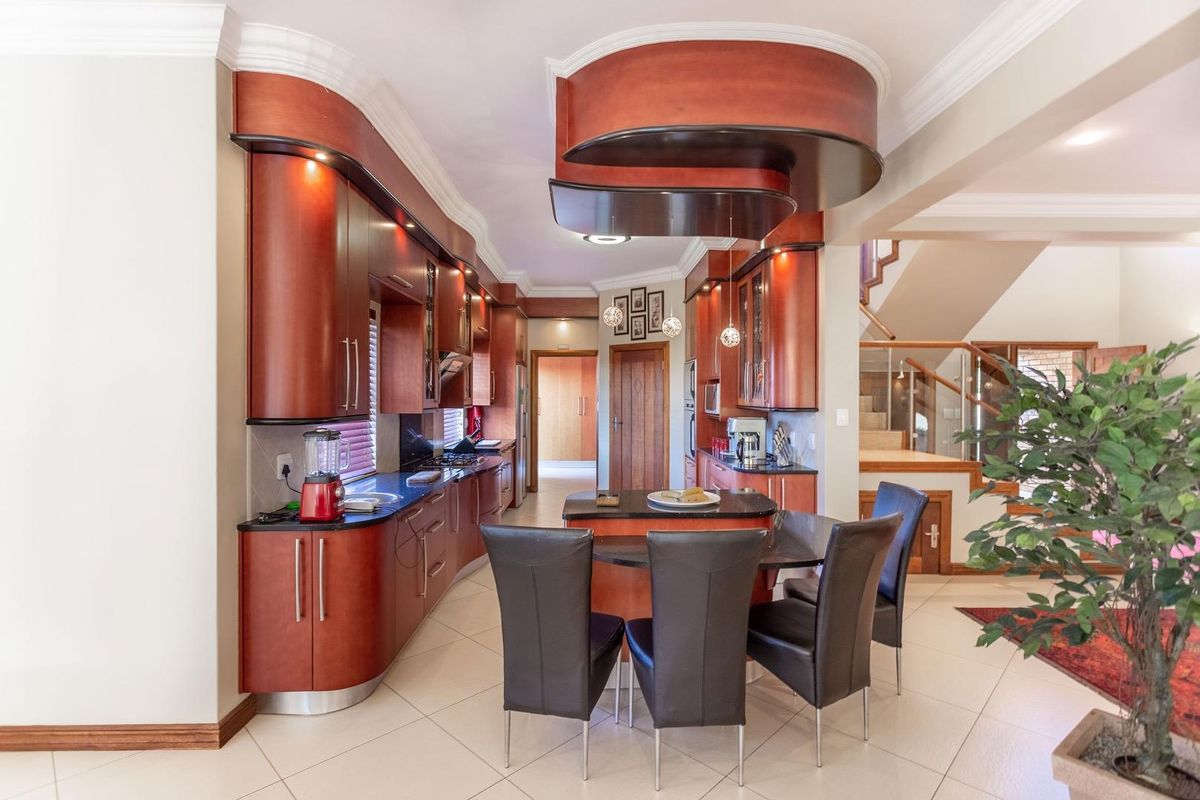 A well-appointed kitchen featuring custom cherry wood cabinetry, granite countertops, a central island with integrated seating, and decorative bulkhead ceiling detailing.