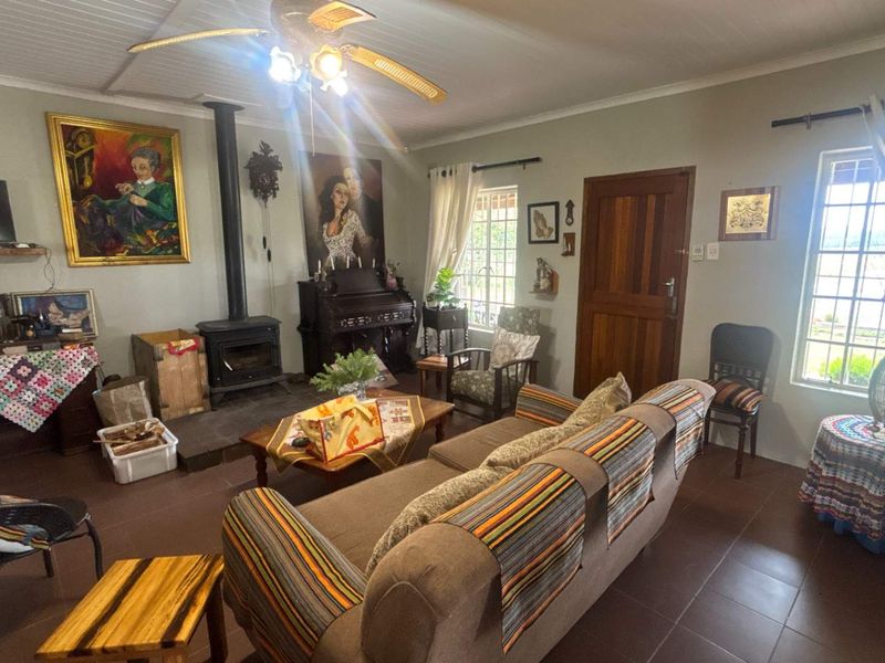 A cozy living room featuring a wood-burning stove, tiled flooring, and a ceiling fan, offering a warm and traditional atmosphere.