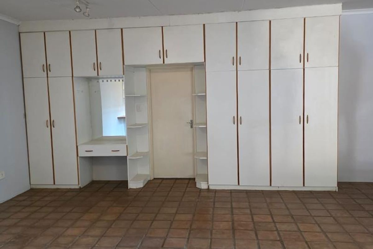 Spacious bedroom featuring extensive built-in cabinetry with an integrated vanity and durable tiled flooring throughout.