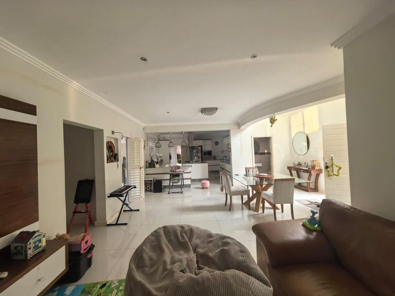 Spacious open-plan living and dining area featuring polished floor tiles, recessed lighting, and a seamless transition into the modern kitchen space.