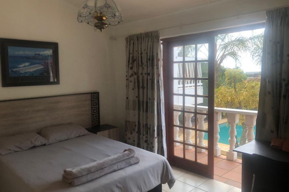 Bedroom featuring tiled flooring and a wooden framed glass door leading to a private balcony overlooking the swimming pool area.