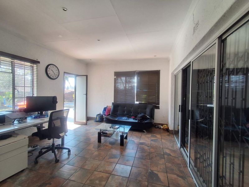 A living area featuring tiled flooring, recessed lighting, and large sliding glass doors providing access to the exterior.