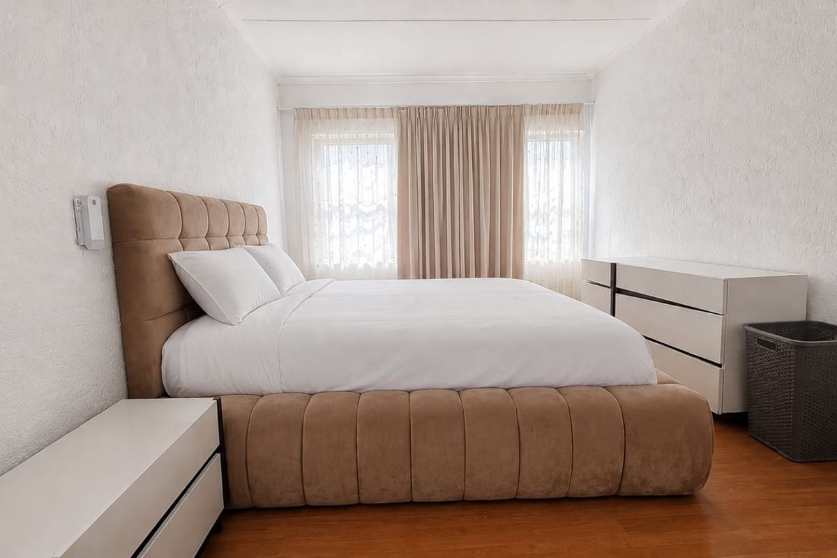A well-lit bedroom featuring laminate flooring and textured walls, providing a neutral and comfortable space.