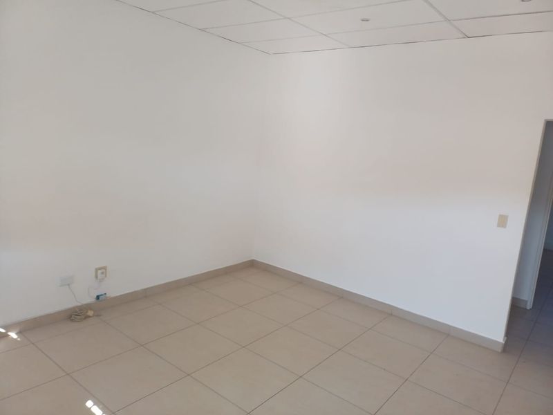 A clean, empty office space featuring neutral tiled flooring and a suspended ceiling, ready for professional fit-out.