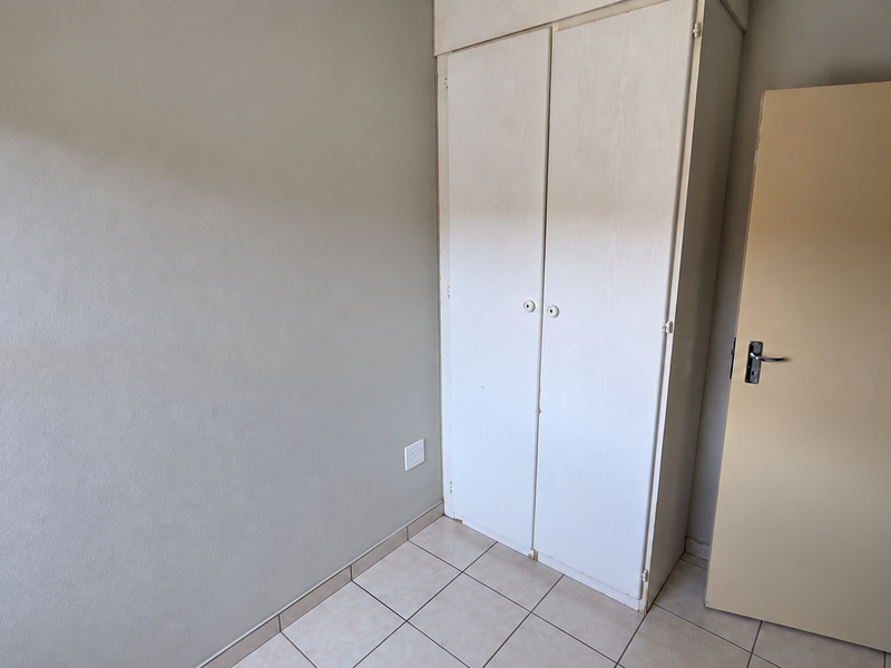 A vacant bedroom featuring tiled flooring and a built-in wardrobe, offering a blank canvas for personalization and interior updates.