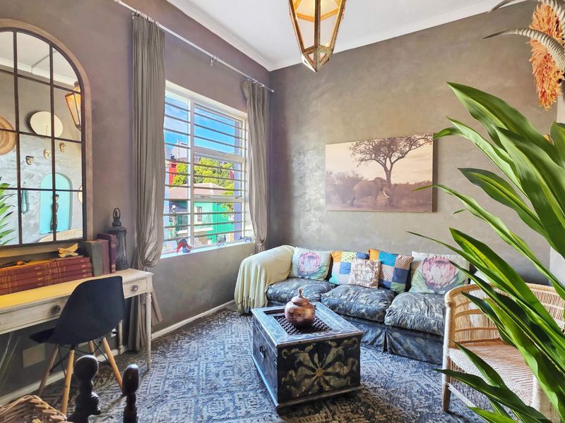 A cozy living room featuring textured walls, a large window with security bars, and a warm, inviting atmosphere.