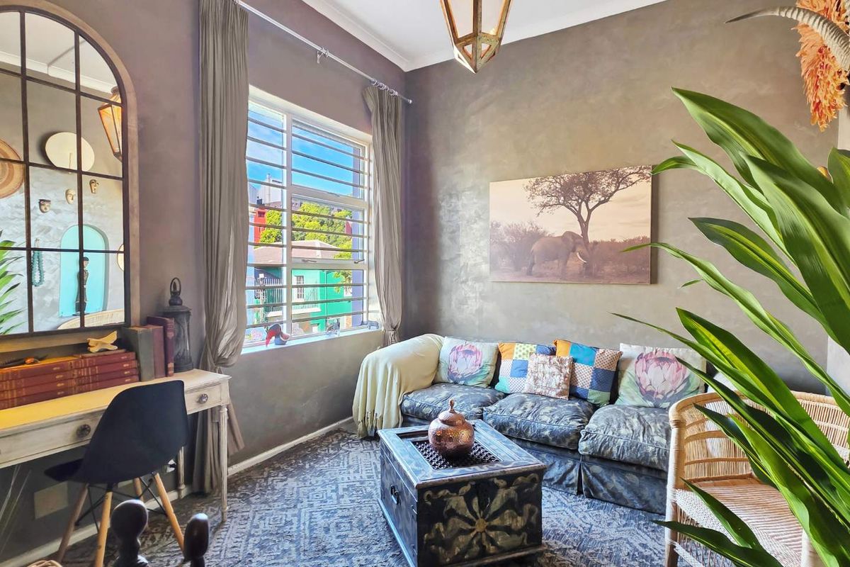 A cozy living room featuring textured walls, a large window with security bars, and a warm, inviting atmosphere.