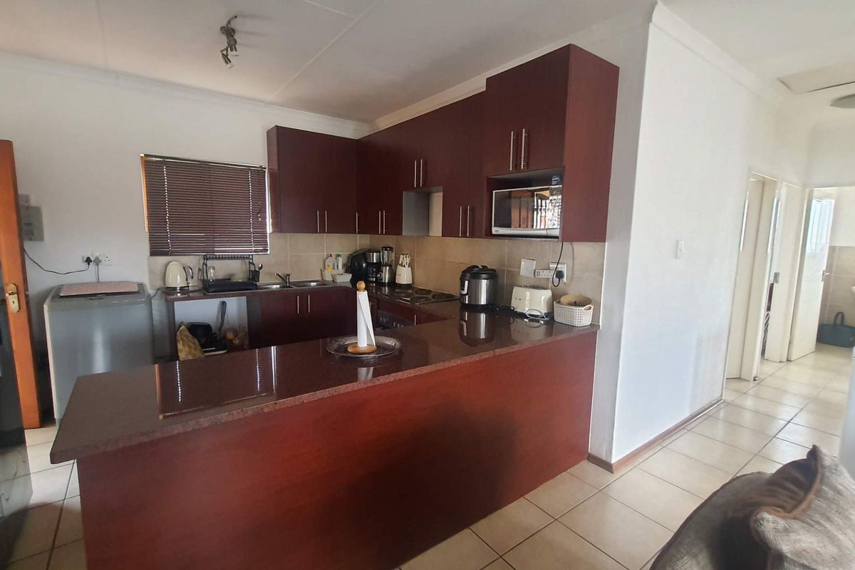 A functional kitchen featuring dark wood cabinetry, granite-style countertops, a breakfast bar, and tiled flooring, providing a practical layout for daily meal preparation.