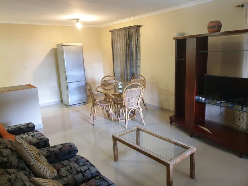 An open-plan living and dining area featuring neutral wall tones and tiled flooring throughout.