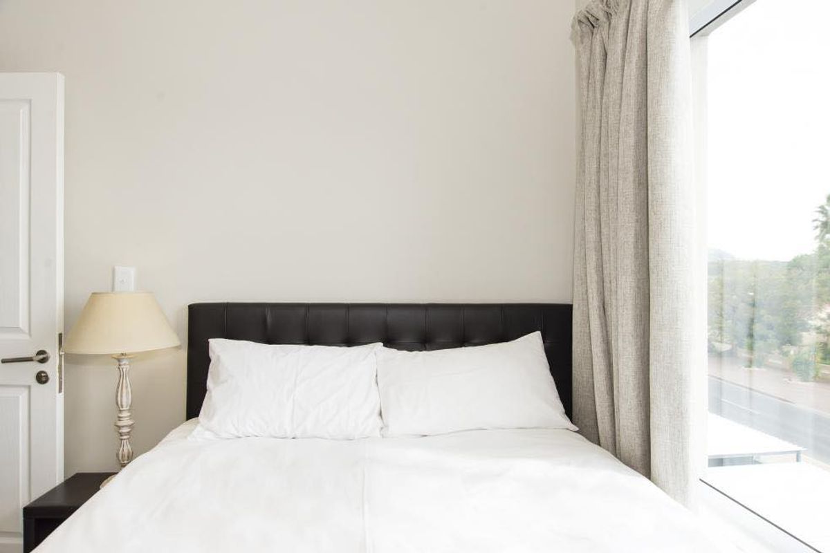 A bright bedroom featuring a large window with floor-to-ceiling curtains, providing natural light and an exterior view.
