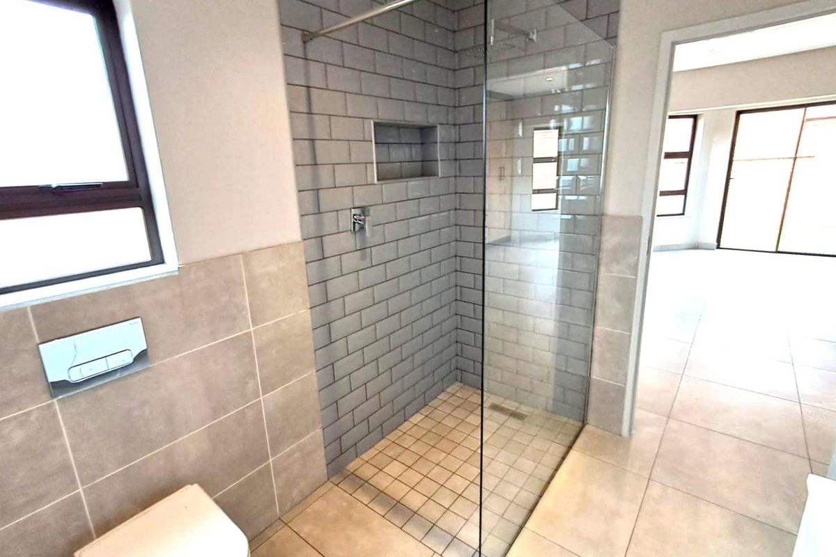 Modern bathroom featuring a walk-in shower with grey subway tile surround, glass screen, and a wall-mounted toilet with concealed cistern.