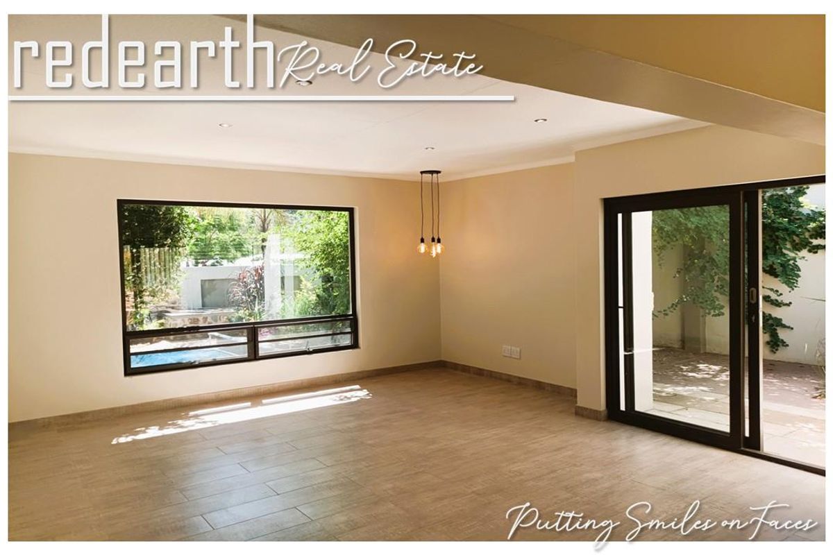 Spacious living area featuring large windows, sliding glass doors leading to the patio, and modern tiled flooring.