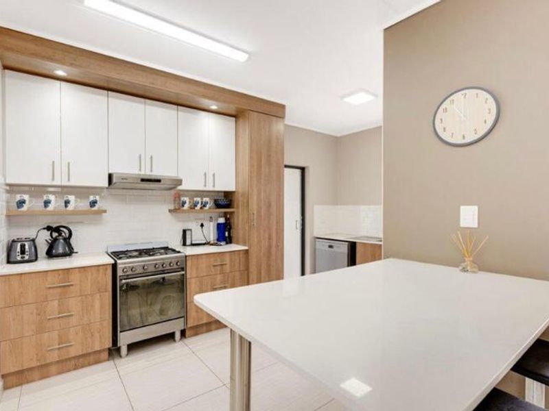 Modern kitchen featuring light wood-tone cabinetry, white stone countertops, a gas stove with extractor, and a convenient breakfast bar area.