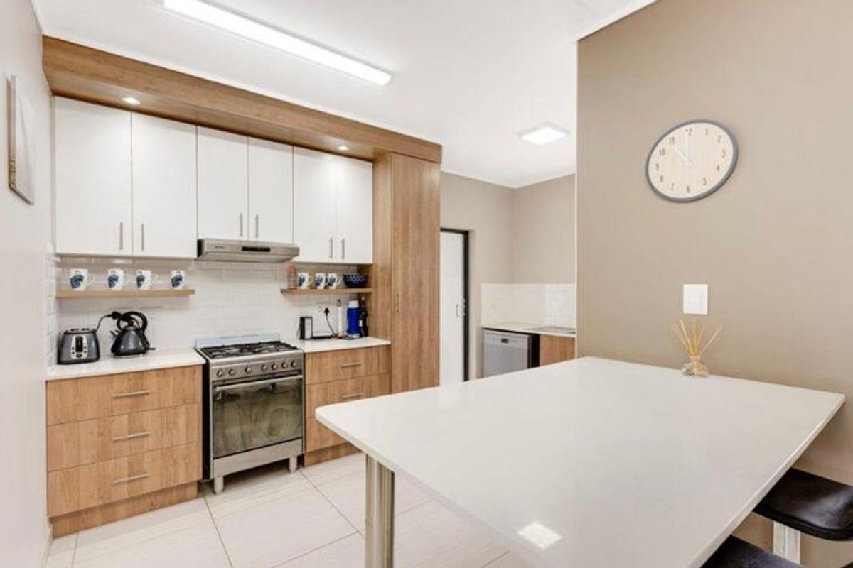 Modern kitchen featuring light wood-tone cabinetry, white stone countertops, a gas stove with extractor, and a convenient breakfast bar area.
