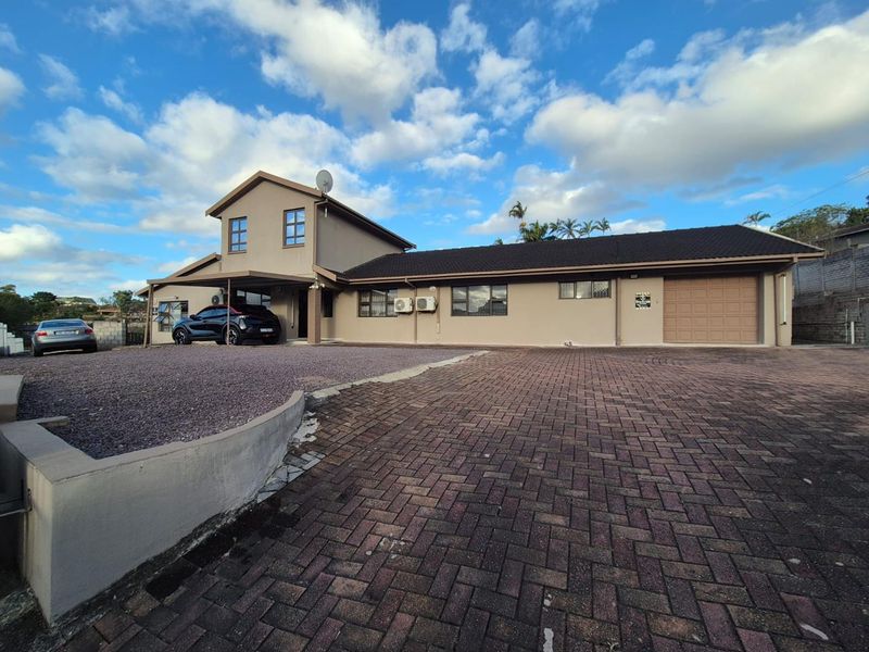 Front elevation of a multi-level house featuring a paved driveway, attached garage, carport, and exterior air conditioning units.