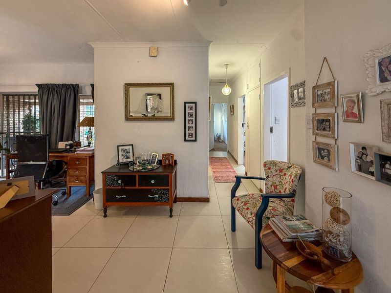 A bright hallway featuring tiled flooring and built-in storage, providing access to adjacent living areas and bedrooms.