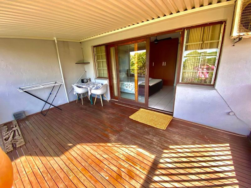 Covered patio area featuring timber decking and direct access to the interior through a sliding glass door.