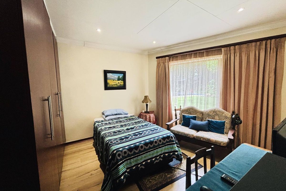A bedroom featuring laminate flooring, built-in cupboards, and recessed ceiling lighting, offering a functional space with large window access.