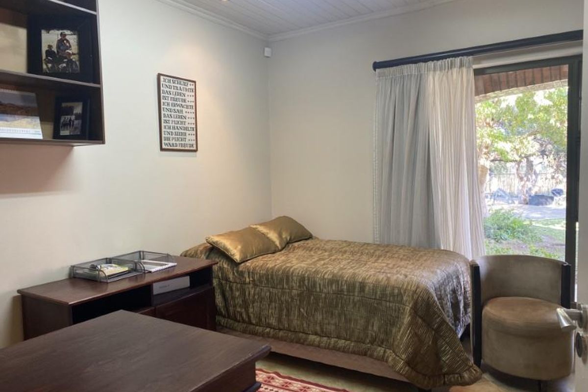 A functional bedroom featuring built-in shelving, recessed ceiling lighting, and a sliding glass door providing direct access to the garden area.