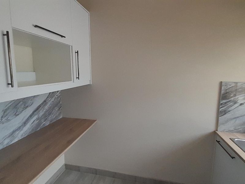 A clean and modern scullery area featuring white cabinetry, marble-effect splashbacks, wood-look laminate countertops, and a stainless steel sink.