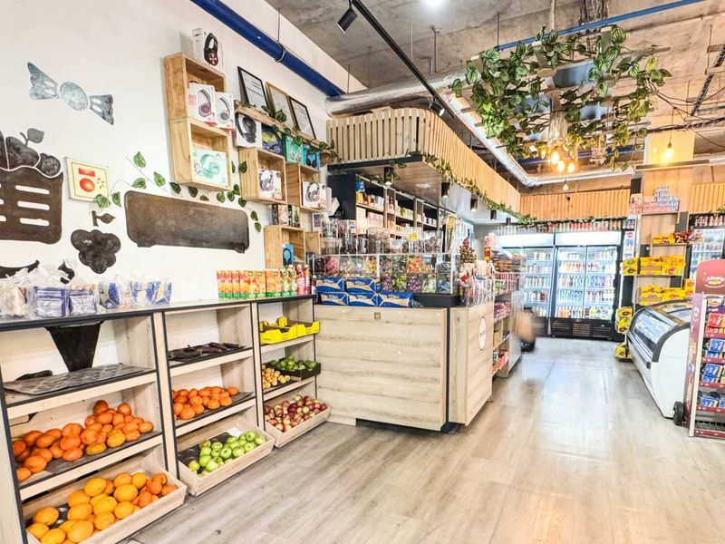 A well-maintained retail space featuring built-in produce shelving, a central service counter, and commercial refrigeration units with modern exposed ceiling finishes.