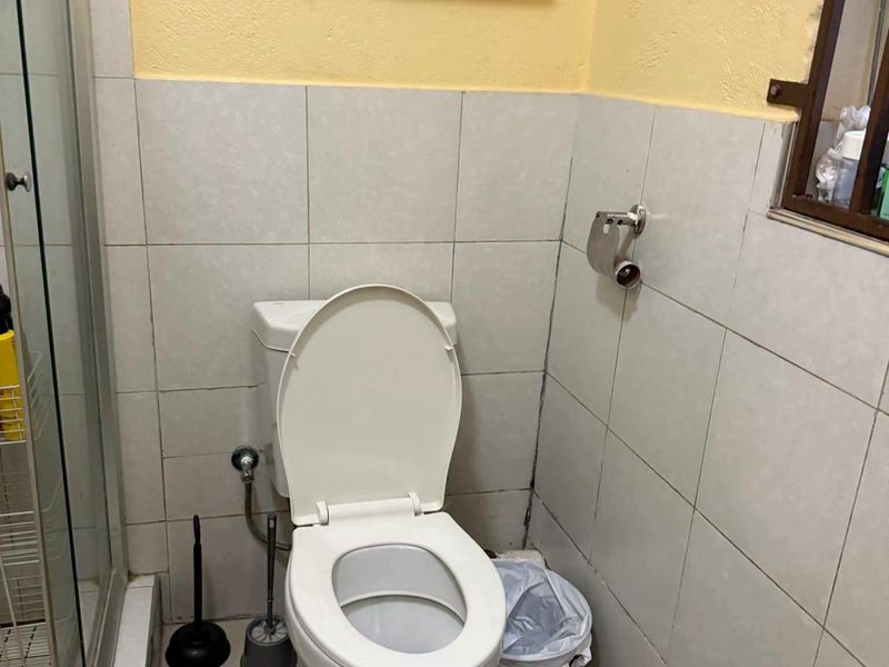 A functional bathroom featuring a standard toilet, shower enclosure, and tiled wall finishes.
