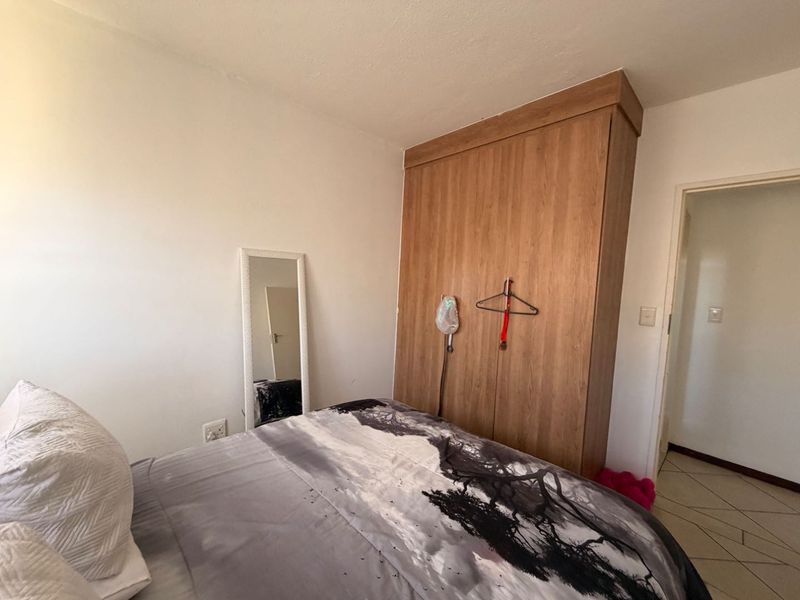 A bedroom featuring a wood-finish built-in wardrobe and tiled flooring, providing functional storage space.