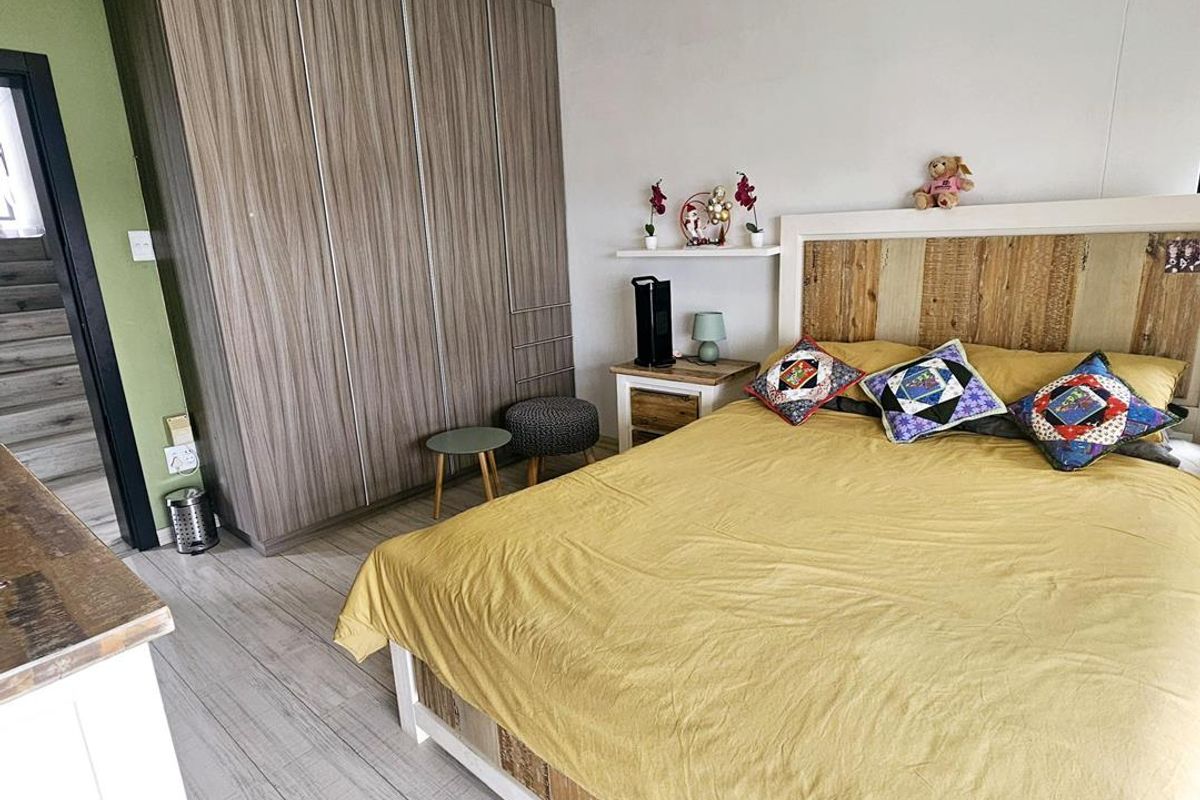 A well-maintained bedroom featuring built-in floor-to-ceiling wooden wardrobes and light-toned wood-look flooring.
