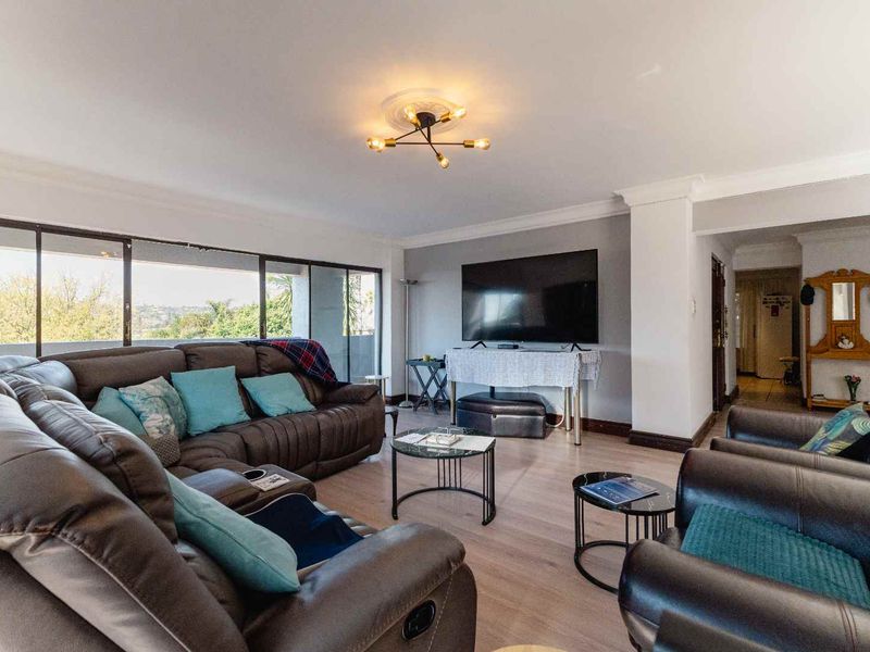 Spacious living room featuring laminate flooring, modern ceiling lighting, and large sliding glass doors that provide ample natural light and outdoor access.