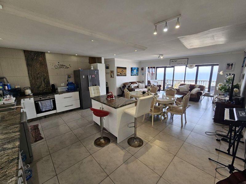 Spacious open-plan kitchen and living area featuring tiled floors, granite countertops, and large sliding doors leading to an outdoor view.
