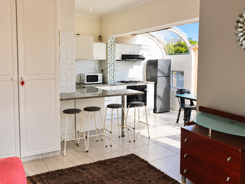 Open-plan kitchen featuring granite countertops, a breakfast bar, subway tile backsplash, and built-in appliances, seamlessly flowing into the living area.