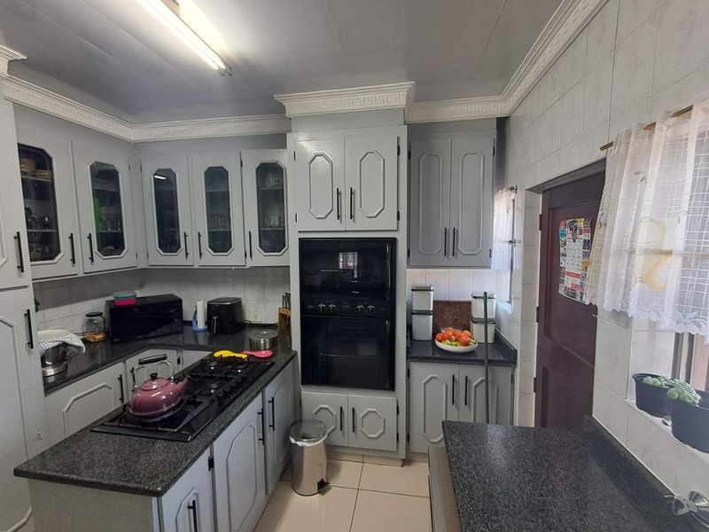 A functional kitchen featuring built-in cabinetry, granite countertops, a gas hob, and a built-in oven with tiled flooring and decorative coved cornicing.