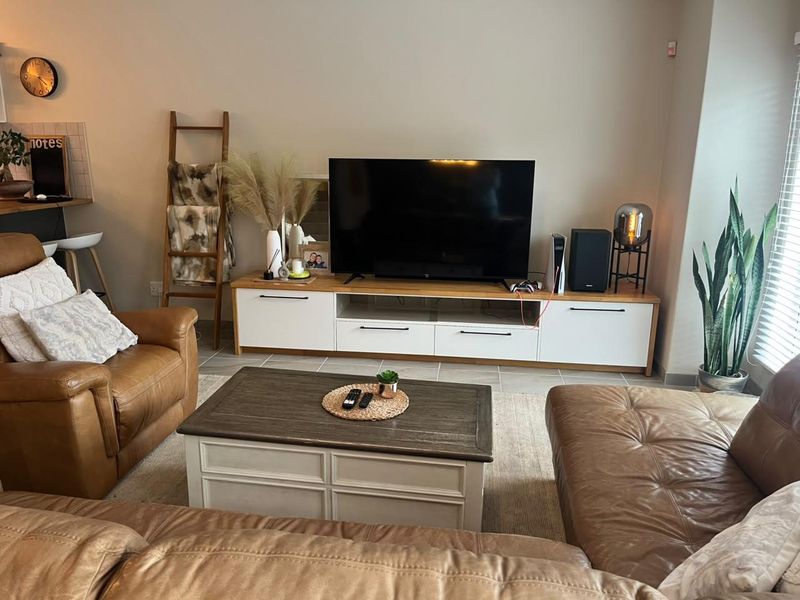 A comfortable living room featuring tiled flooring and venetian blinds, providing a bright and functional space for relaxation.