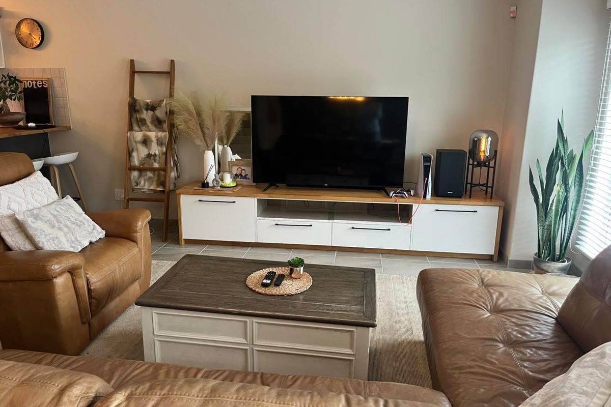 A comfortable living room featuring tiled flooring and venetian blinds, providing a bright and functional space for relaxation.