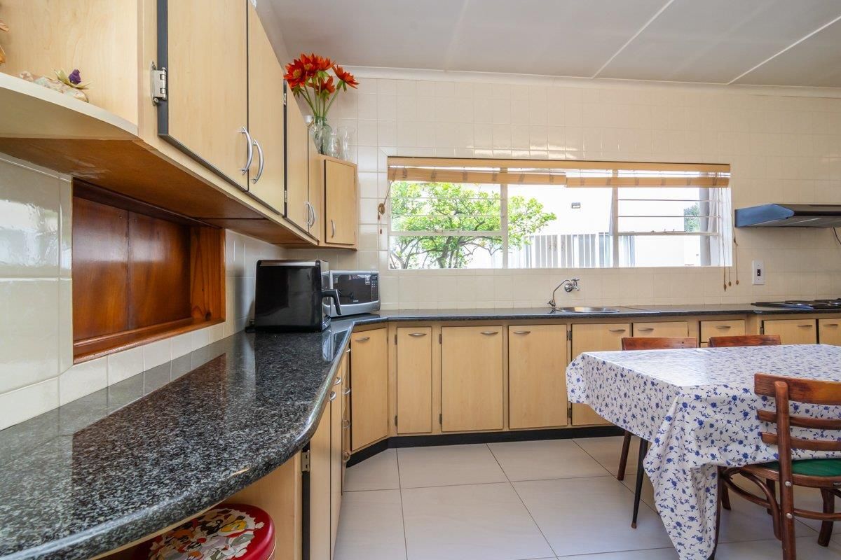 A functional kitchen featuring light wood cabinetry, dark granite countertops, tiled splashbacks, and a built-in extractor fan.